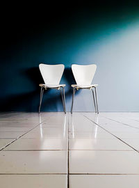 Empty chair against white wall