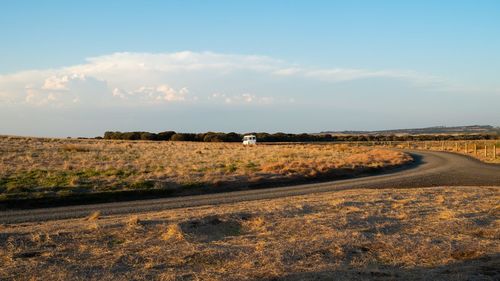 Road amidst field against sky