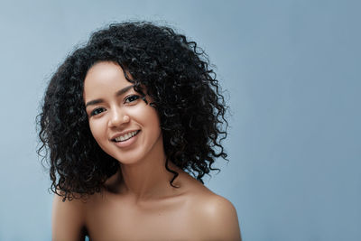 Portrait of young woman against blue background