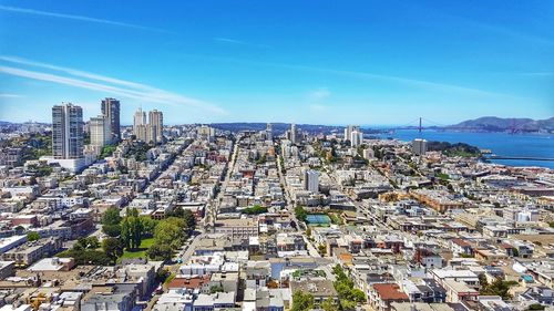 High angle view of buildings and sea against blue sky