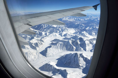 Aerial view of snowcapped mountains seen through airplane window