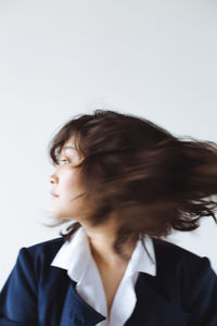 Side view of young woman looking away against white background