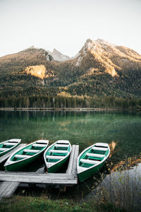 Boats moored on lake against mountains