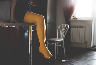 Low section of woman sitting on chair at home