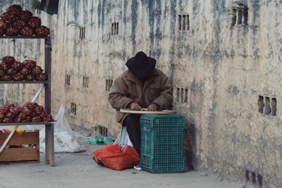 Man sitting on seat against wall