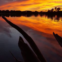 Scenic view of lake against dramatic sky during sunset