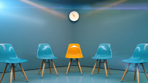 Empty chairs and table against blue wall