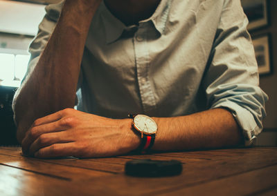 Midsection of man with smart watch sitting at table