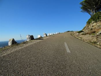 Road on beach against clear blue sky