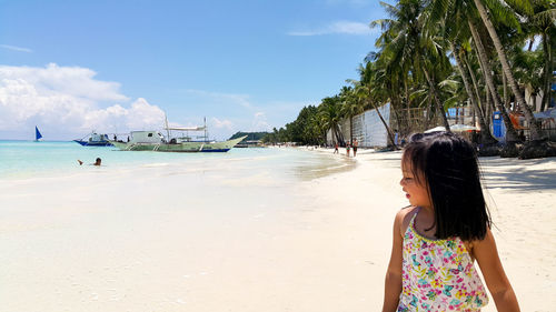 Little girl standing at beach on sunny day