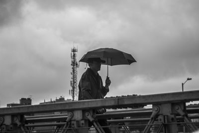 Low angle view of man with umbrella against sky