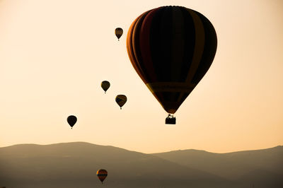 Silhouette of hot air balloons with landscape and mountain against sky - stock photo