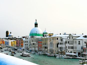 View of buildings by canal against clear sky