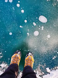 Low section of person standing on frozen lake