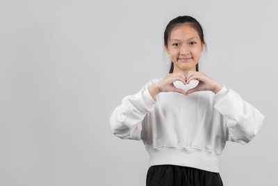 Portrait of smiling girl standing against white background