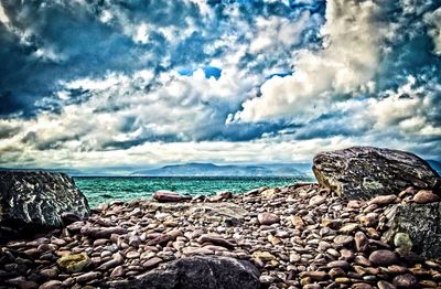 View of rocky beach against cloudy sky