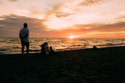 Couple at beach against sky during sunset