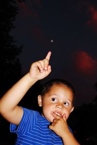 Cute boy pointing up during night