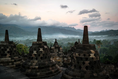 Old stupas against mountains during sunset