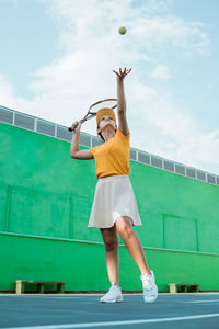 Full length of young woman playing tennis