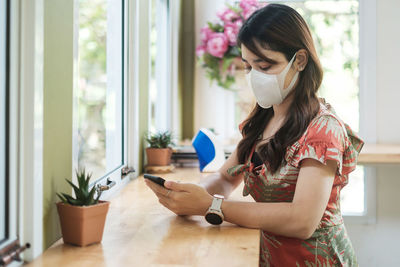 Young woman wearing mask using mobile phone