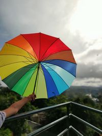 Person holding umbrella against sky