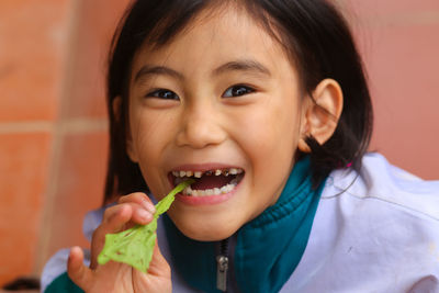 Portrait of cute girl eating leaf mustard