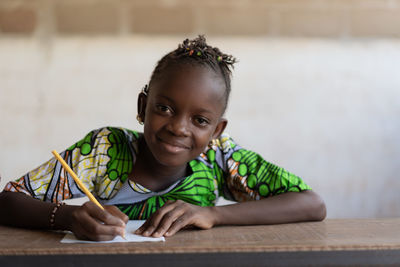 Portrait of smiling girl sitting on table