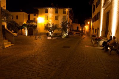 Illuminated street amidst buildings at night