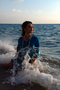 Beautiful young woman on beach against sky