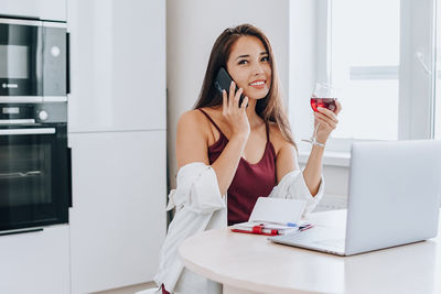 Young woman using laptop on table at home