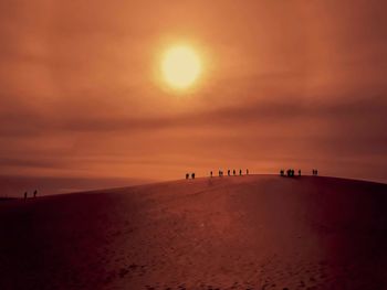 Silhouette people on beach against sky during sunset