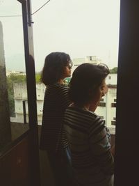 Side view of two women looking through window