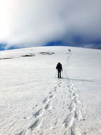 Rear view of person walking on snowcapped landscape against sky