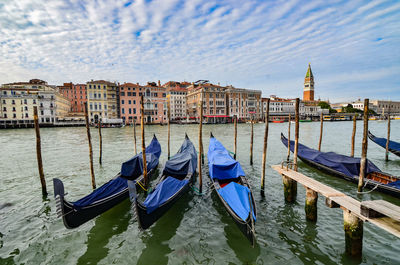 Boats moored on canal against buildings in city