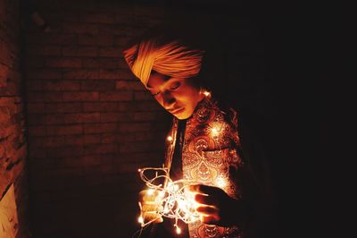 Young man holding illuminated light painting in dark