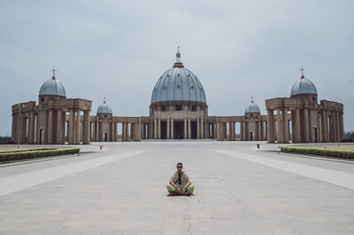 Man sitting outside temple against sky