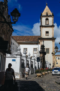 People on street by buildings against sky in city