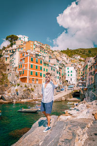 Portrait of man standing at beach against buildings in city