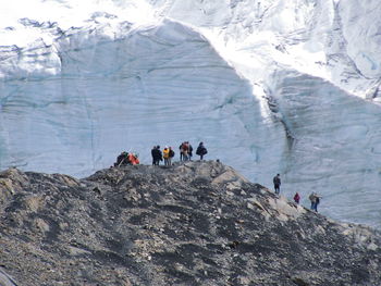 People on snowcapped mountain against sky