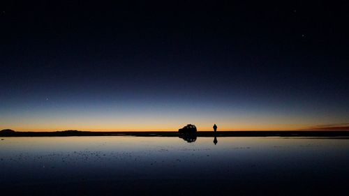 Silhouette boat in lake against clear sky at night