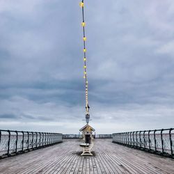 Communications tower on pier against sky