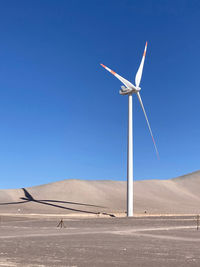 Low angle view of windmill against clear blue sky