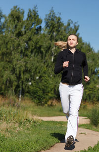 Full length of young woman jogging on pathway at park