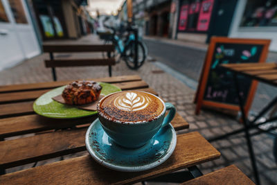 Cup of cappucino shot in front of a paved raod in the center of carlow, ireland on an early morning.