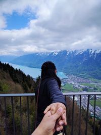 Close-up of man holding woman hand against mountain