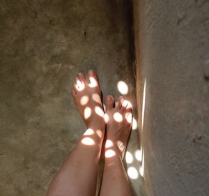 Low section of woman with shadow on tiled floor