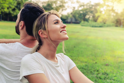 Young couple sitting back to back on grass