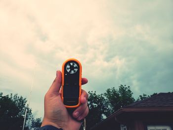 Man photographing with mobile phone against sky