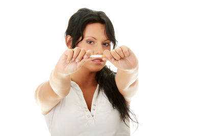 Portrait of young woman holding ice cream against white background